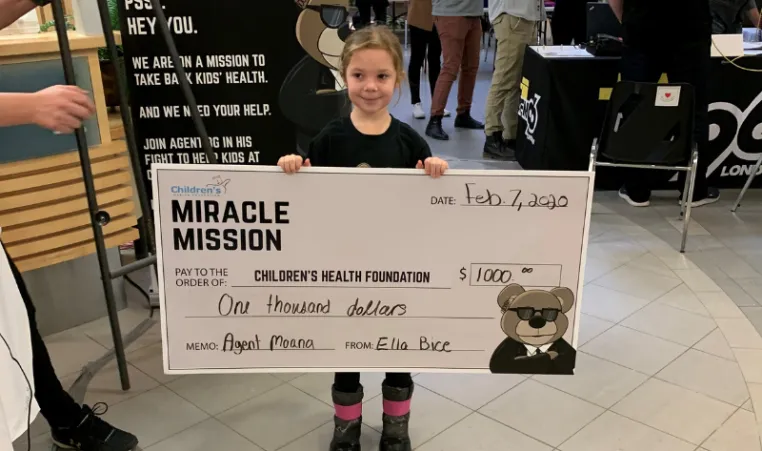 Ella holds a cheque for $1000 dollars she helped raise for the Children's Hospital.