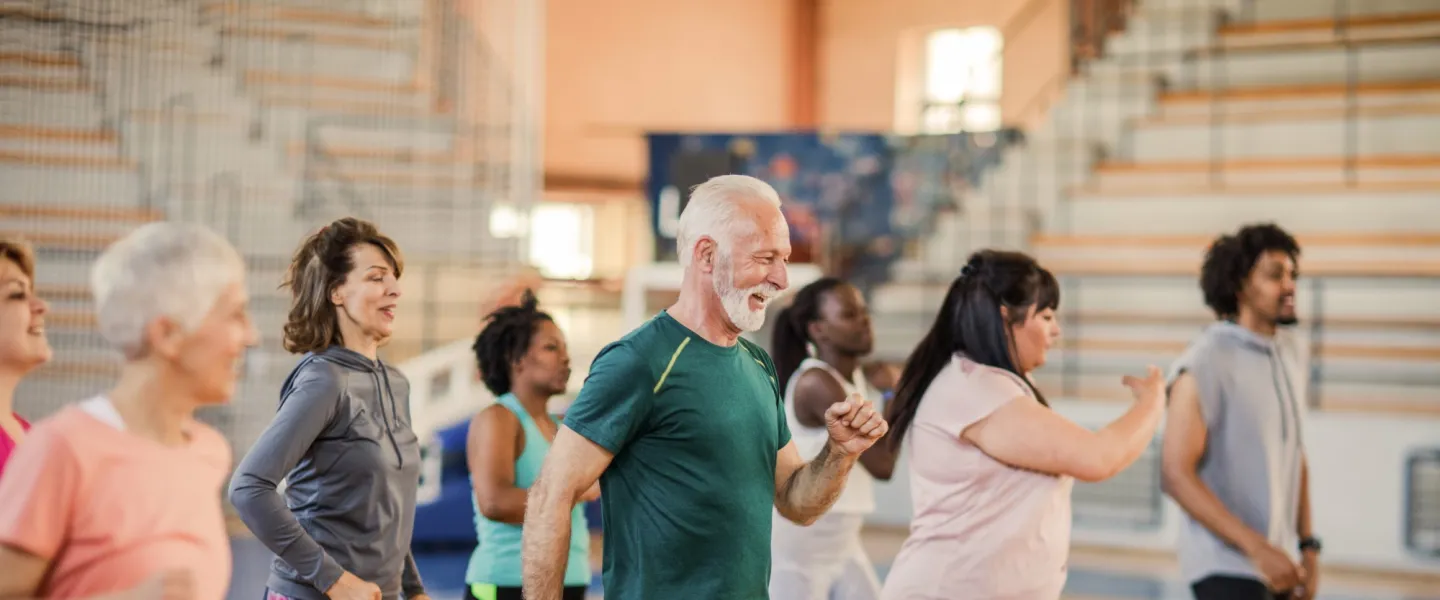 A diverse group of people participate in a fitness class at the Y.