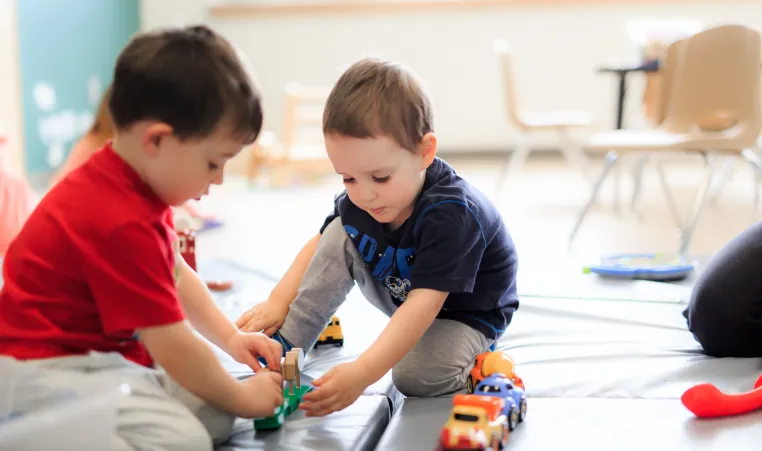 Two young boys play with toy cars at a YMCA Child Care centre.