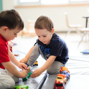 Two young boys play with toy cars at a YMCA Child Care centre.