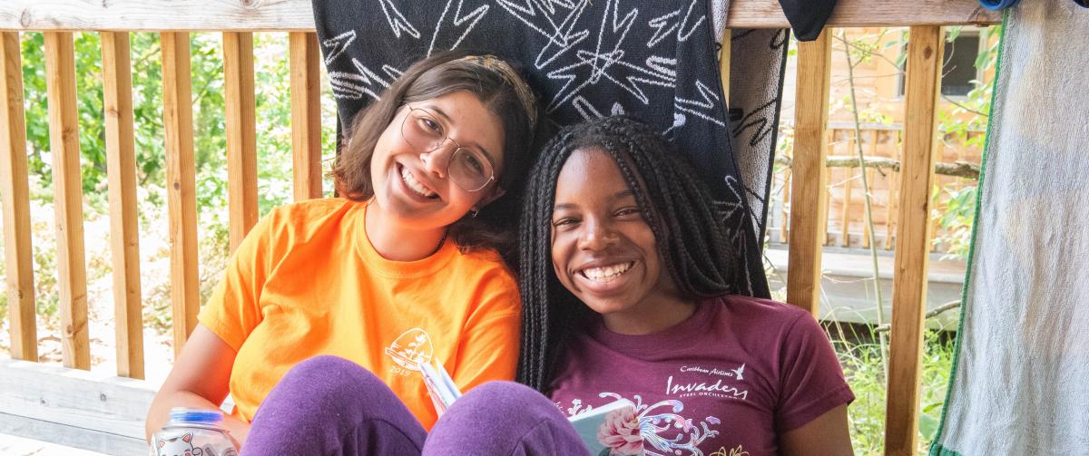CQE Camp Counselor and Camper sitting on their cabin porch during free time.