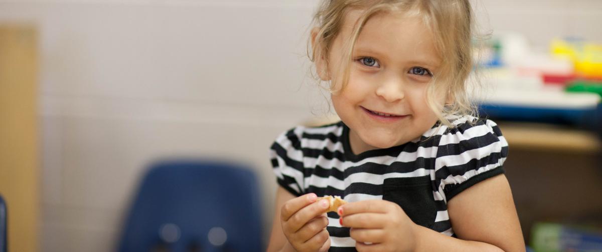 Smiling little girl enjoying her snack at after care