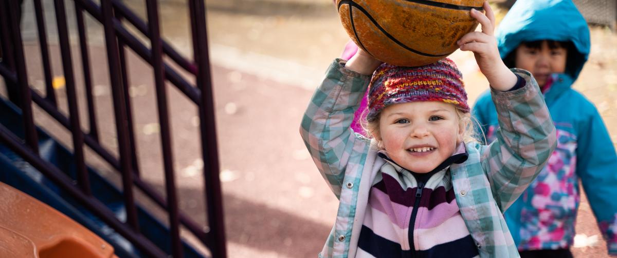 Little girl playing outside with a basketball