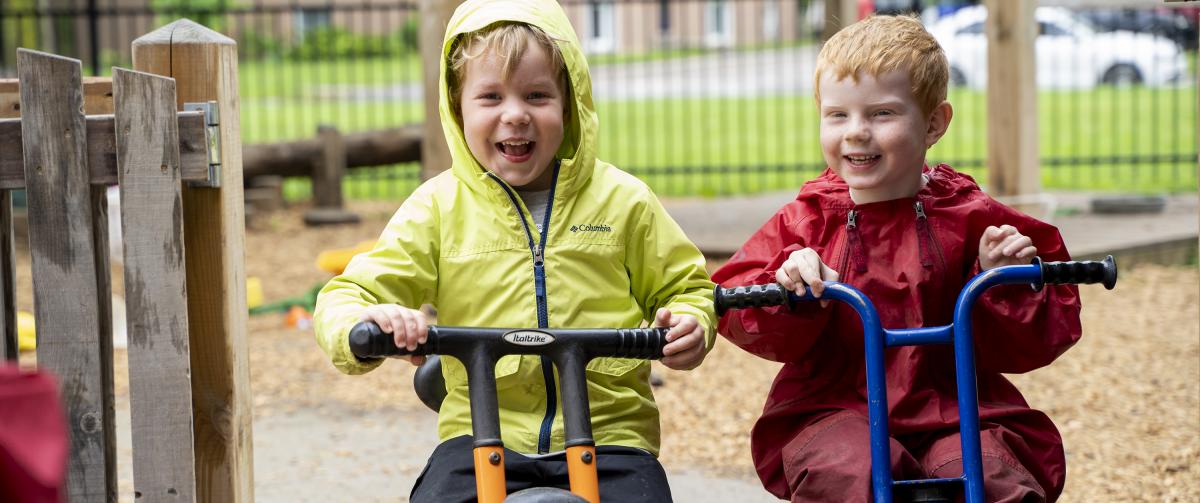 Two boys riding bikes outside