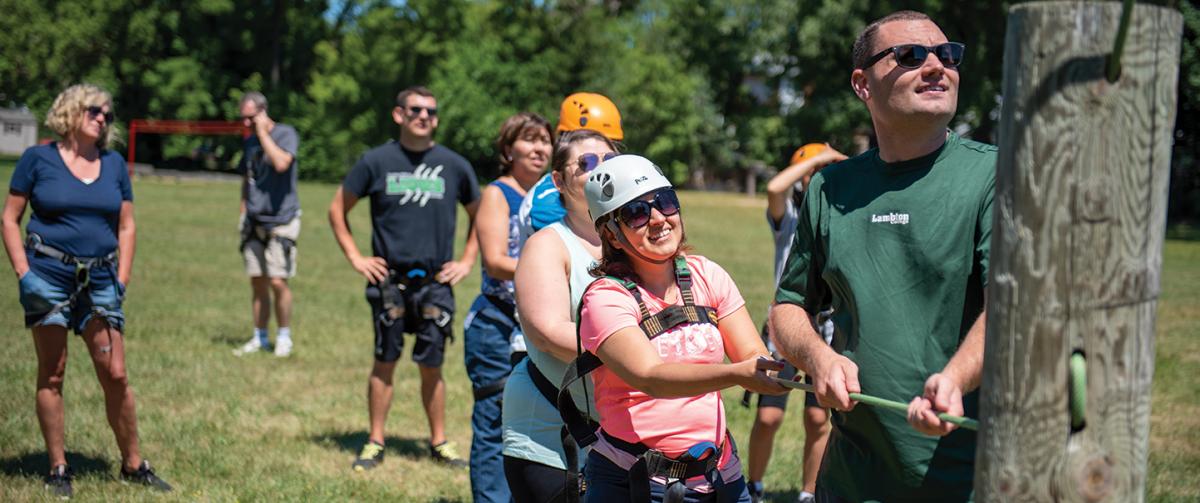 A group working together, holding the ropes that would be supporting those on the high ropes course.